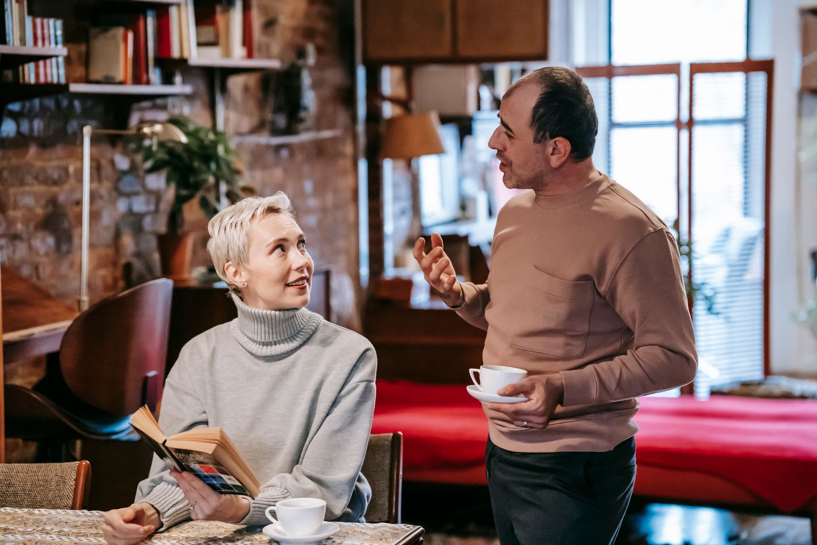 A middle-aged couple reading together and talking over coffee at home